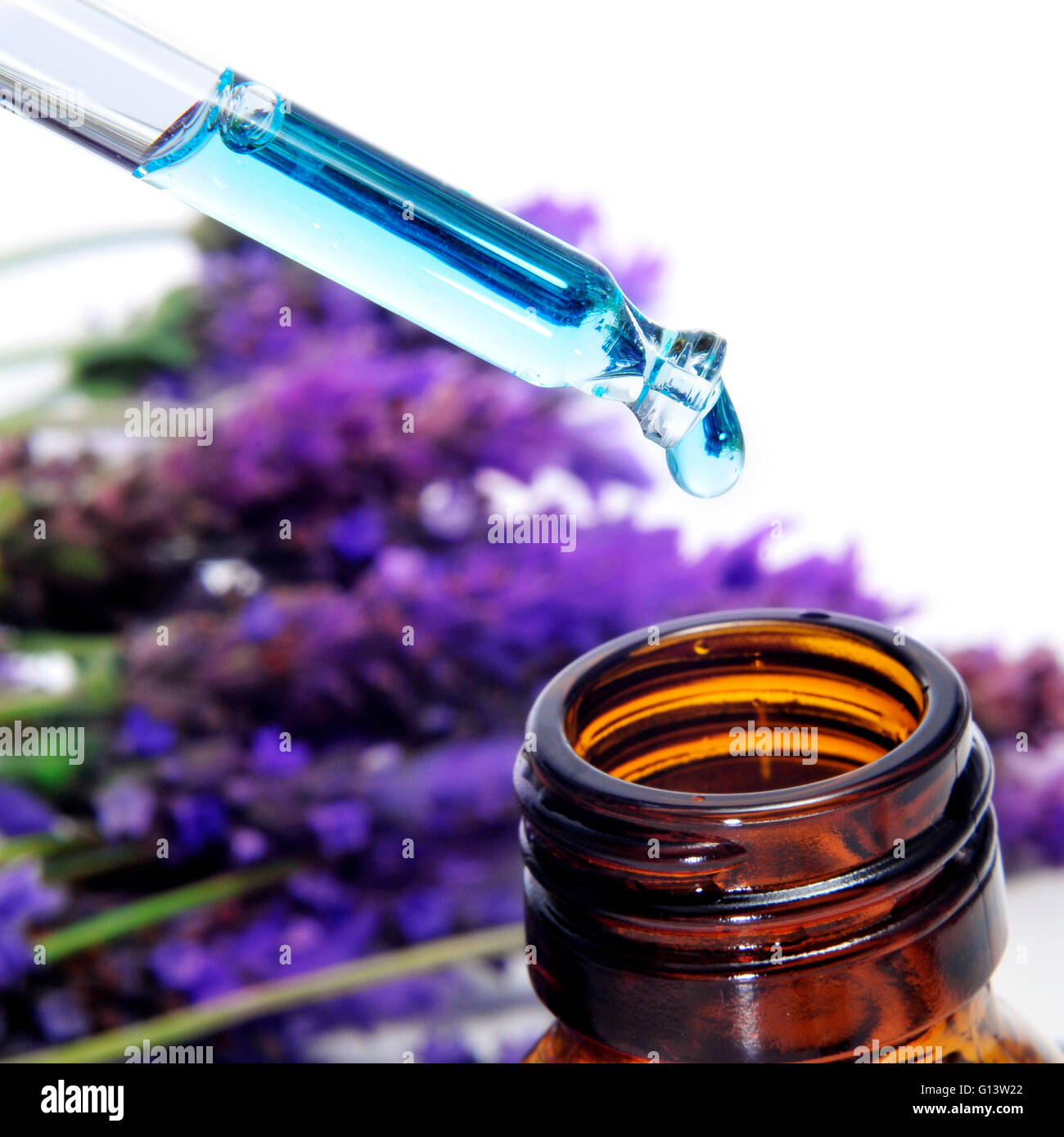 a pile of lavender flowers and a dropper bottle with lavender essence Stock Photo