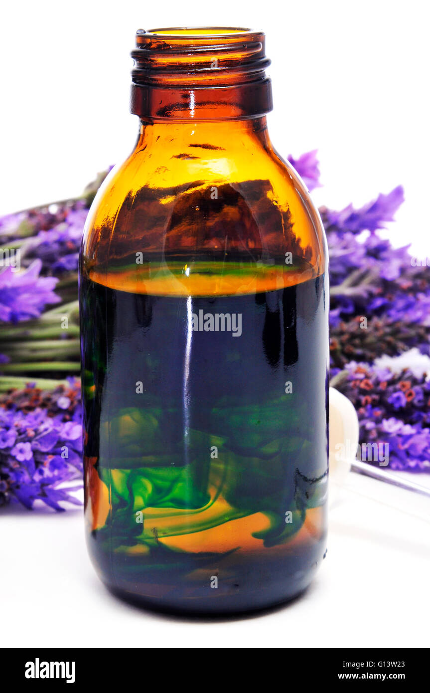 a pile of lavender flowers and a dropper bottle with lavender essence Stock Photo