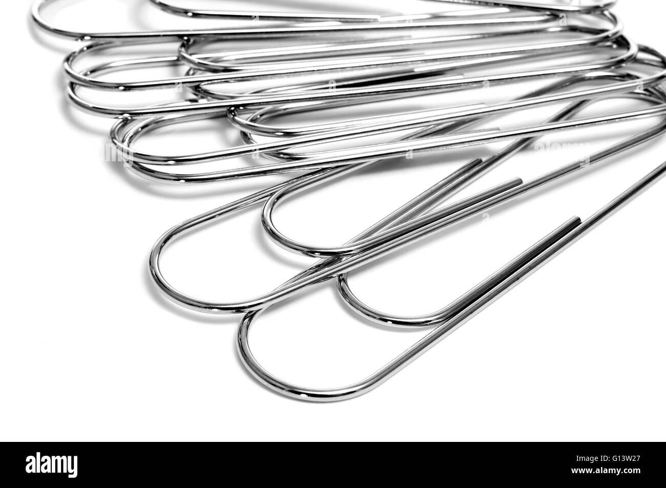 a pile of metallic paperclips on a white background Stock Photo