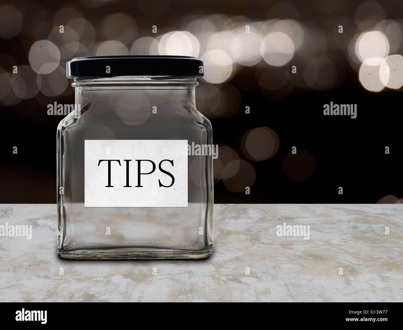 Low wage issue. Empty tips jar, bokeh background suggests bar/restaurant. Stock Photo