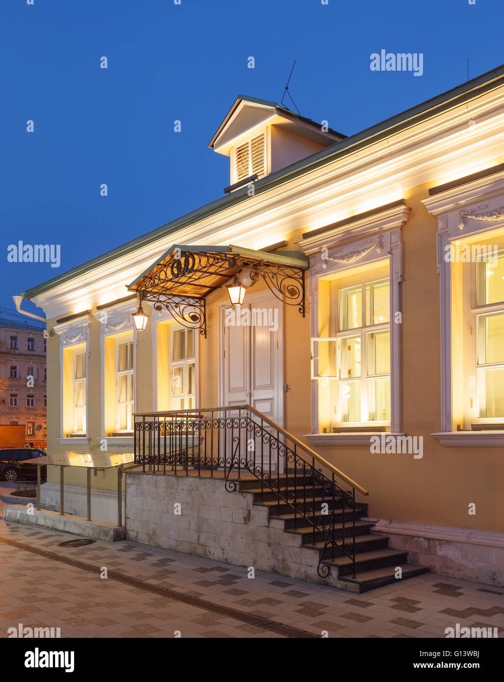 A single storey building in classical palladio style with yellow walls and evening architectural lighting. Moscow, Russia Stock Photo