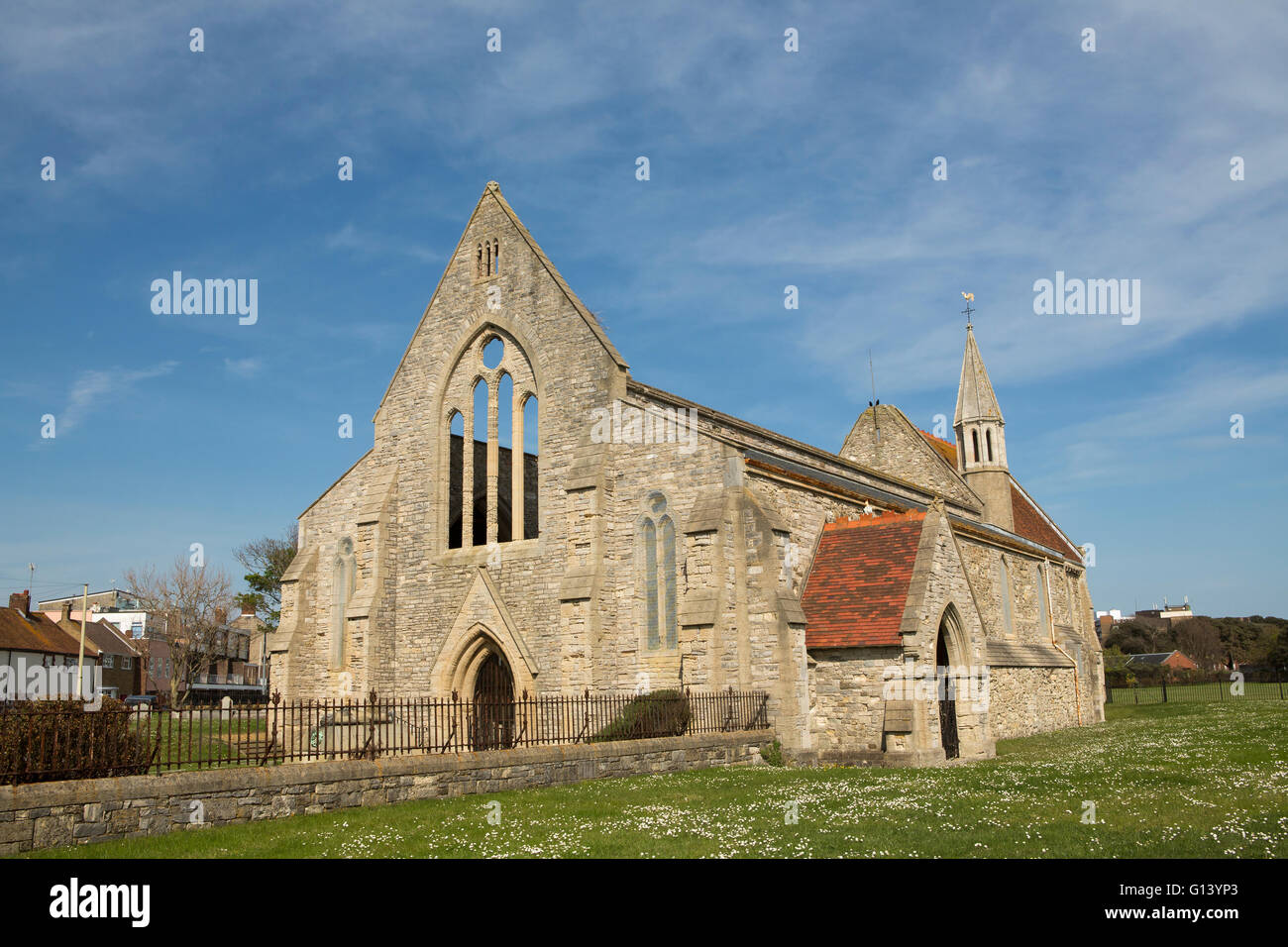 Garrison church in old Portsmouth. Damaged in WWII it still stands without a roof. Blue sky day with daisies in the grass field. Stock Photo