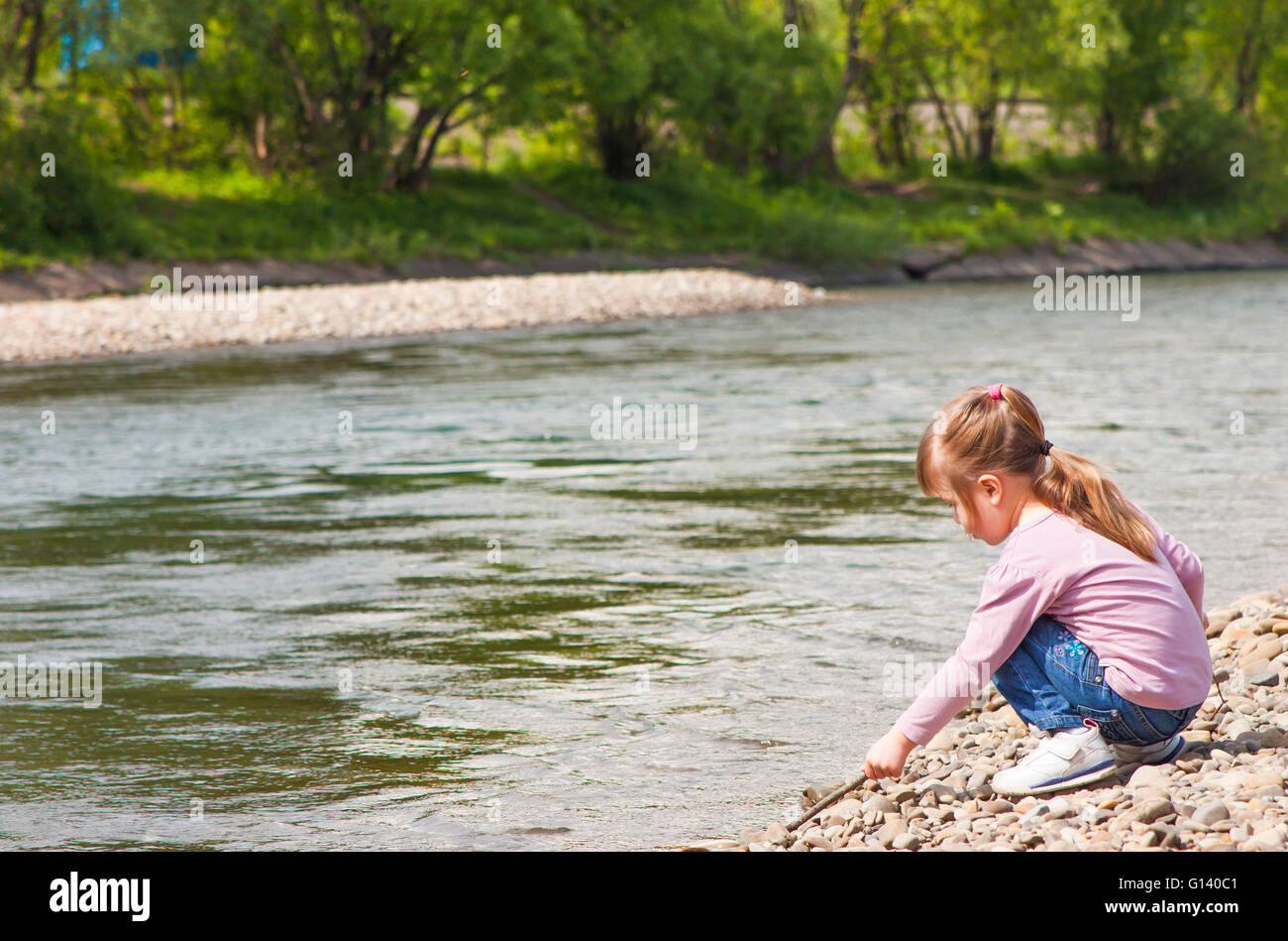 Little girl playing near river Stock Photo - Alamy