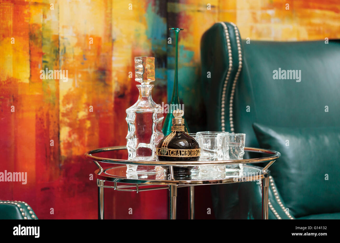 Alcohol decanter, bottle of Chambord liqueur, red wine and glasses on a glass serving table