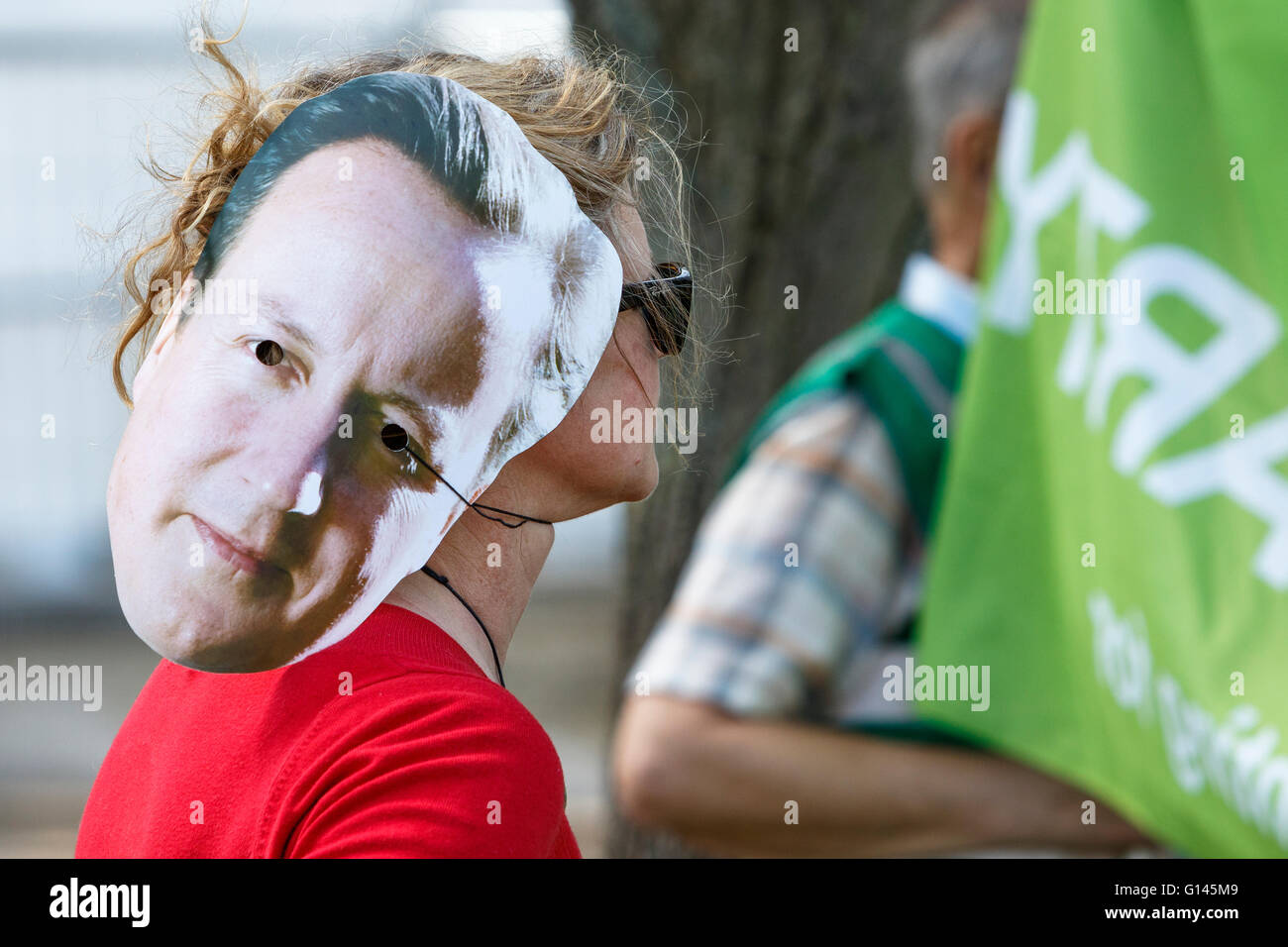 Bristol, UK, 8th May, 2016.  A protester is pictured wearing a David Cameron face mask as she listens to speeches at the end of the 'Going backwards for climate change' march. Credit:  lynchpics/Alamy Live News Stock Photo