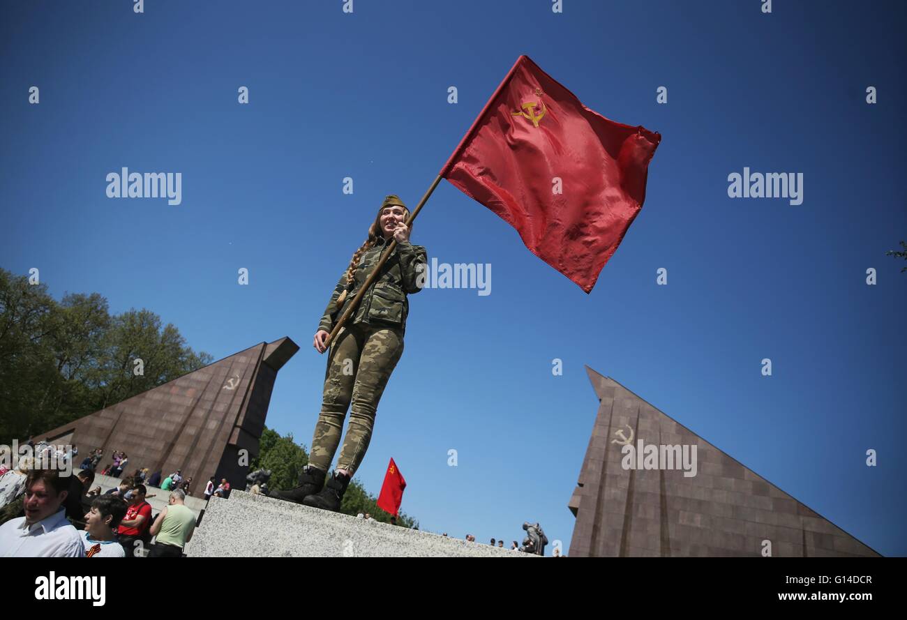 Berlin, Germany. 09th May, 2016. A young woman in a soldier's uniform carrying a flag commemorates the end of World War Two at the Soviet memorial in Treptow in Berlin, Germany, 09 May 2016. The motorcycle gang 'Night Wolves' commemorated the end of the Second World War and the victory over fascism. 09 May is 'Victory Day' in Russia. Photo: KAY NIETFELD/dpa/Alamy Live News Stock Photo