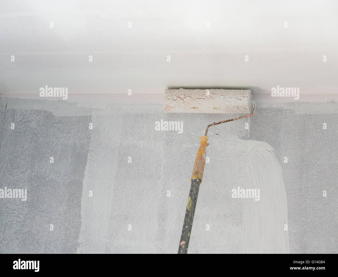 painting a wall and ceiling with painting roller Stock Photo Alamy