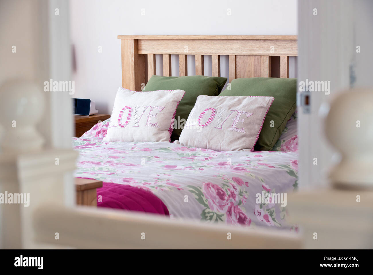 A lifestyle image of a dressed bed in a family home, with pillows emblazoned with the word love on them Stock Photo