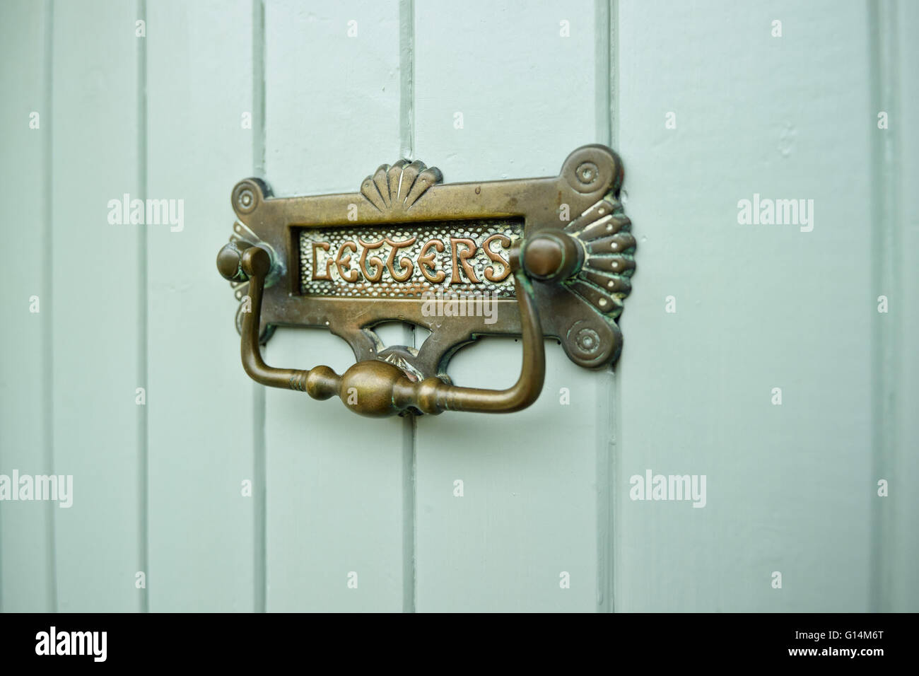A traditional brass letterbox & knocker combined displaying the word letters. Set into a duck