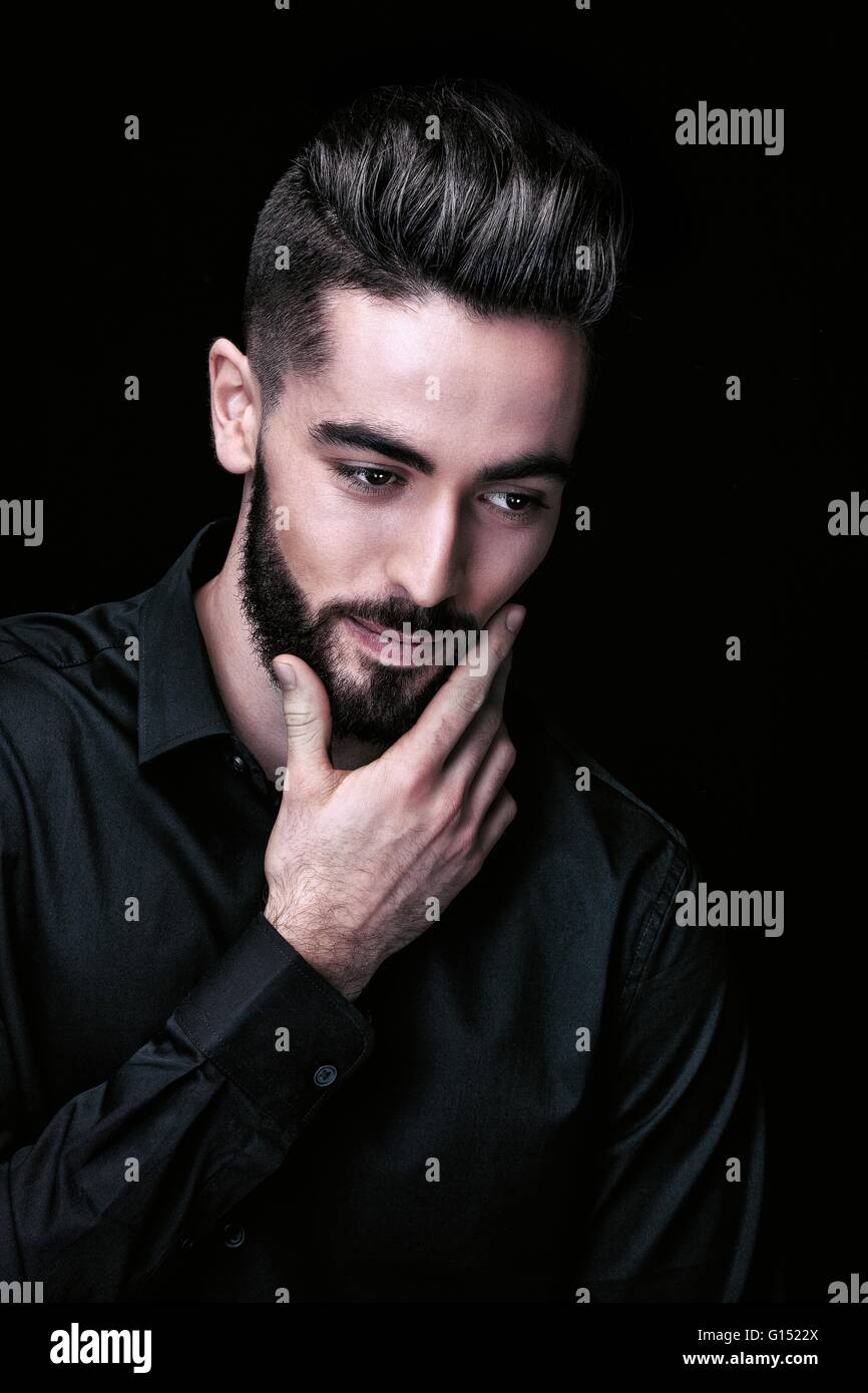 Portrait of a young man, hand on chin, looks down Stock Photo