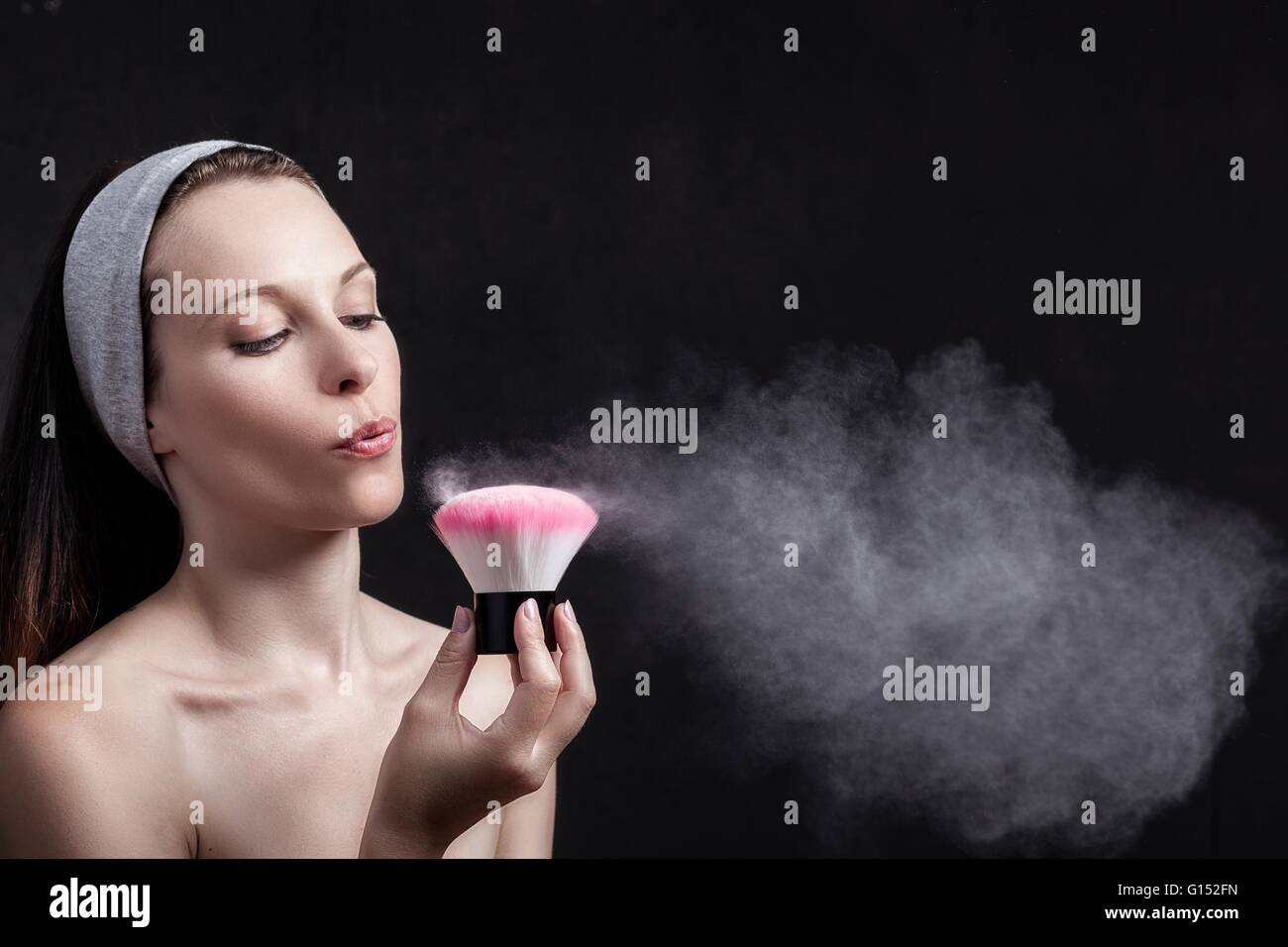 Young woman blows on a makeup brush Stock Photo