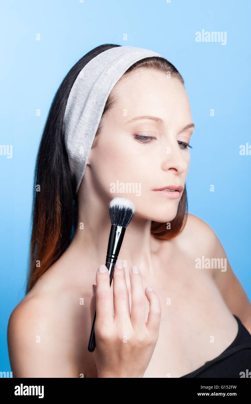Portrait of a woman using make-up brush on face Stock Photo