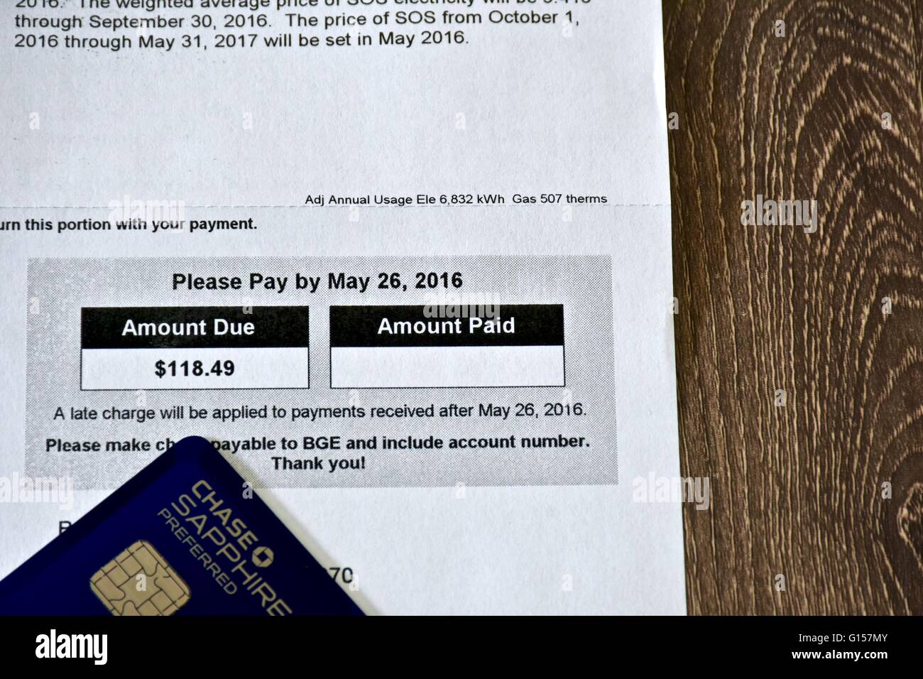 Utility bill laying on a wood surface next to the Chase Sapphire Preferred ultimate rewards credit card. Stock Photo