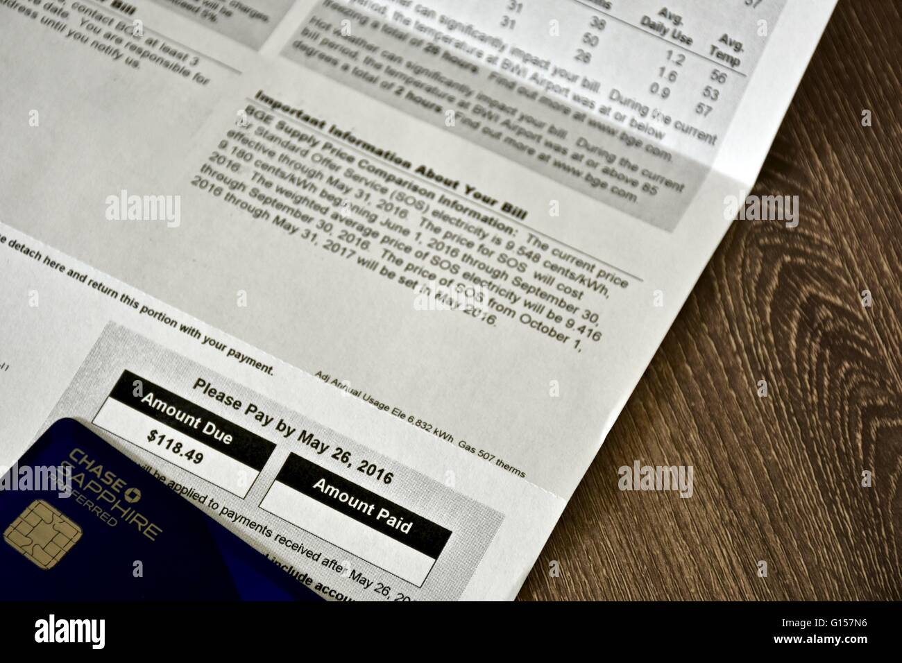 Utility bill laying on a wood surface next to the Chase Sapphire Preferred ultimate rewards credit card. Stock Photo