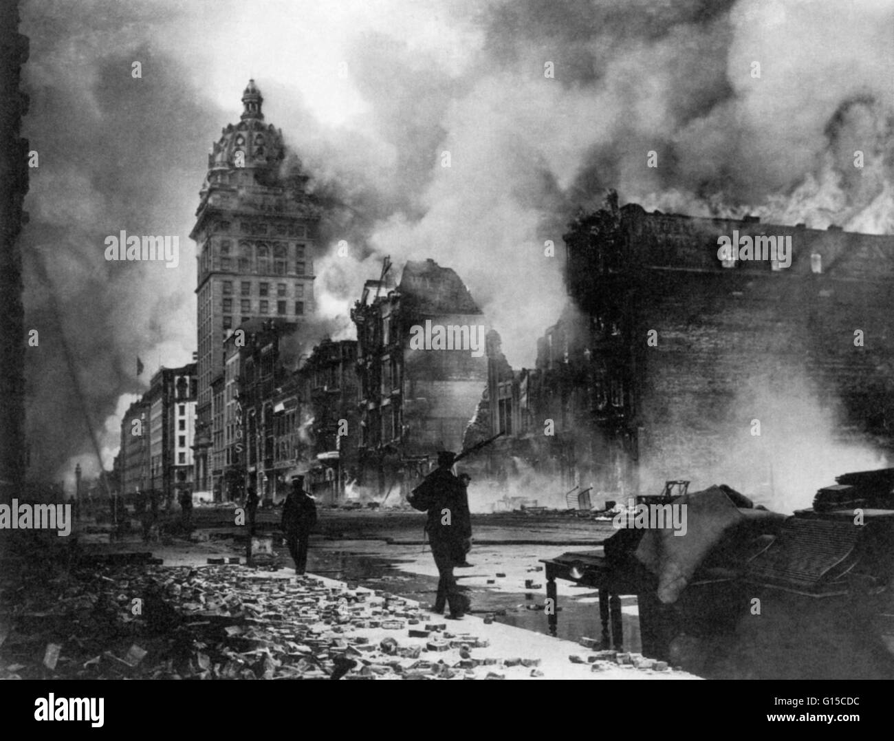 Troops from the Presidio walk east along Market Street after the San Francisco earthquake of 1906. Part of their mission was to protect private and public property as well as to assist police and firefighters. Smoke is billowing out of the tall Call Build Stock Photo