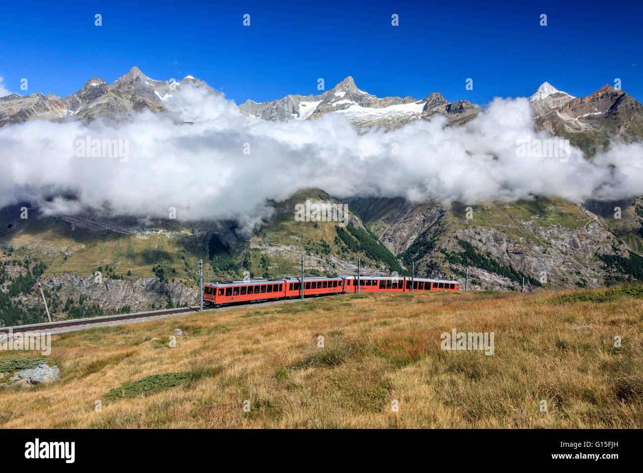 The Bahn train on its route with high peaks and mountain range in the background, Canton of Valais, Swiss Alps, Switzerland Stock Photo