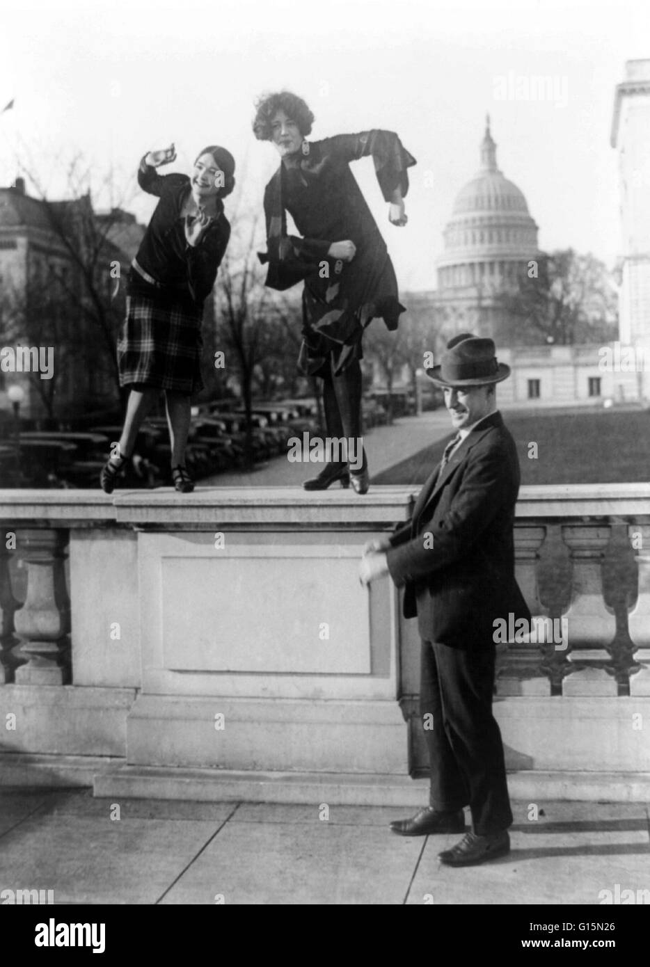 Rep. T.S. McMillan of Charleston, S.C. with flappers, Miss Ruth Bennett and Miss Sylvia Clavins, who are doing the Charleston on railing, with U.S. Capitol in background, 1926. Flappers were a new breed of young Western women in the 1920s who wore short s Stock Photo
