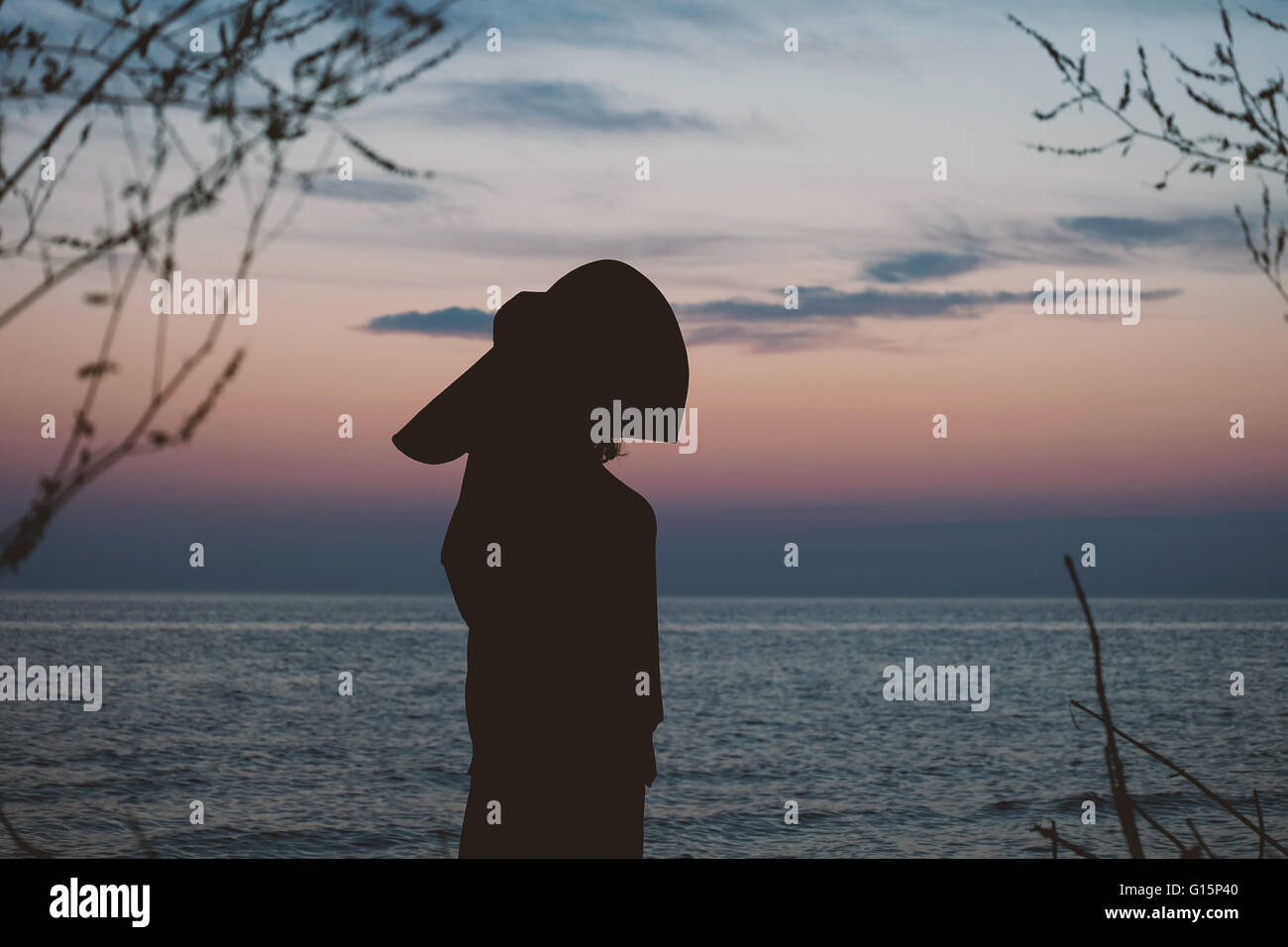 Beautiful silhouette of a woman watching the sunset on the beach in ...