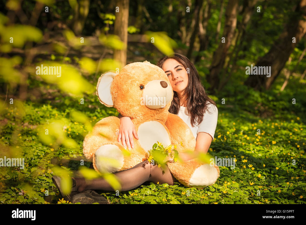 girl with teddy bear sitting on grass in forest Stock Photo - Alamy