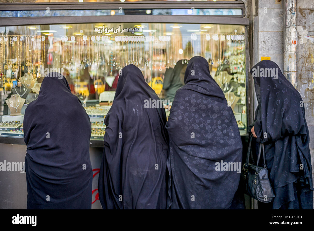 Iranian women in black chadors window shopping at jewelry store in