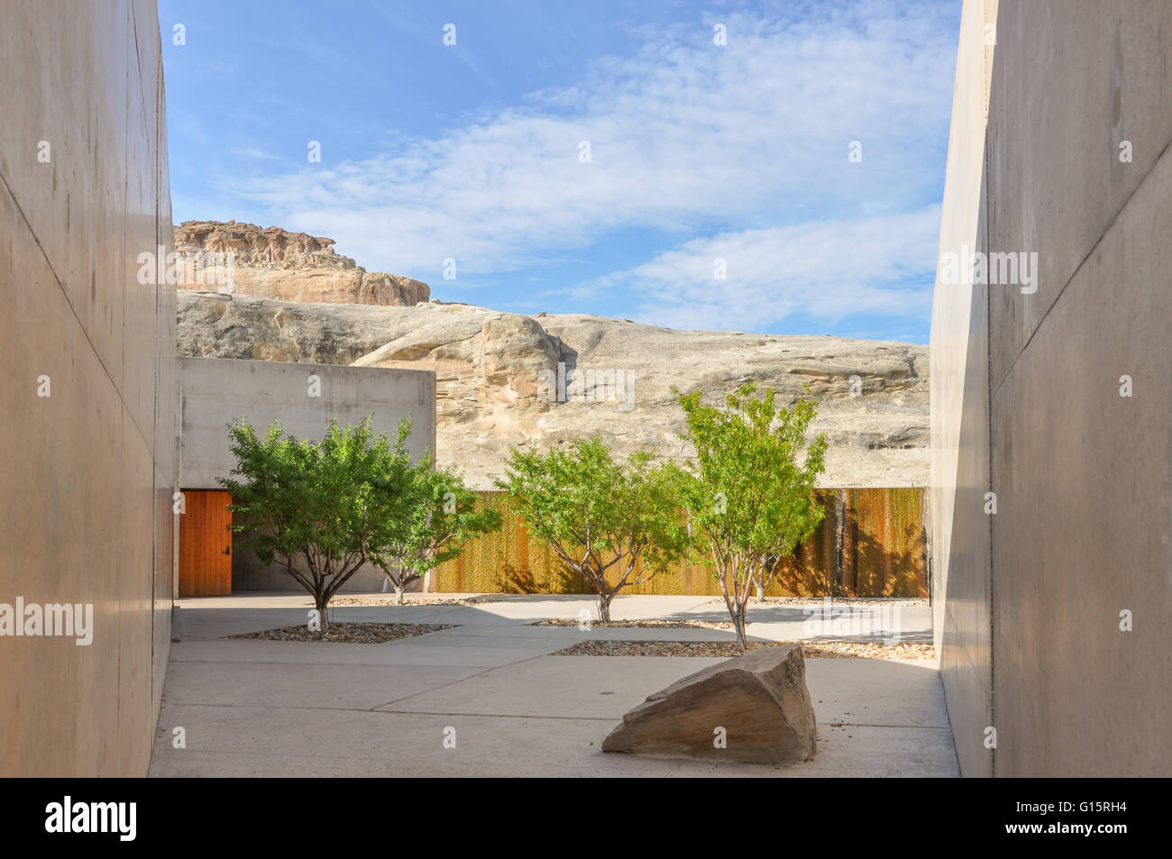concrete walls surrounding a terrace with green trees and rock formations at a Utah resort, Amangiri Stock Photo