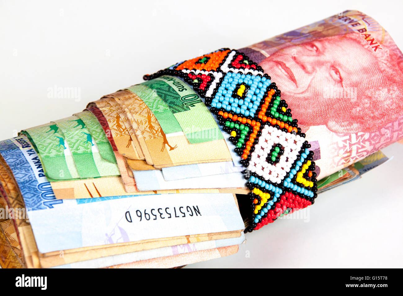 Roll of south African banknotes secured with band of Zulu beads Stock Photo