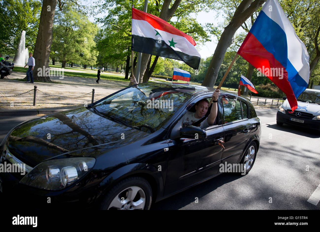 Berlin, Germany. 09th May, 2016. A car with a Russian and Syrian flag drives past the Soviet memorial in Treptow in Berlin, Germany, 09 May 2016. The motorcycle gang 'Night Wolves' commemorated the end of the Second World War and the victory over fascism. 09 May is 'Victory Day' in Russia. Photo: KAY NIETFELD/dpa/Alamy Live News Stock Photo