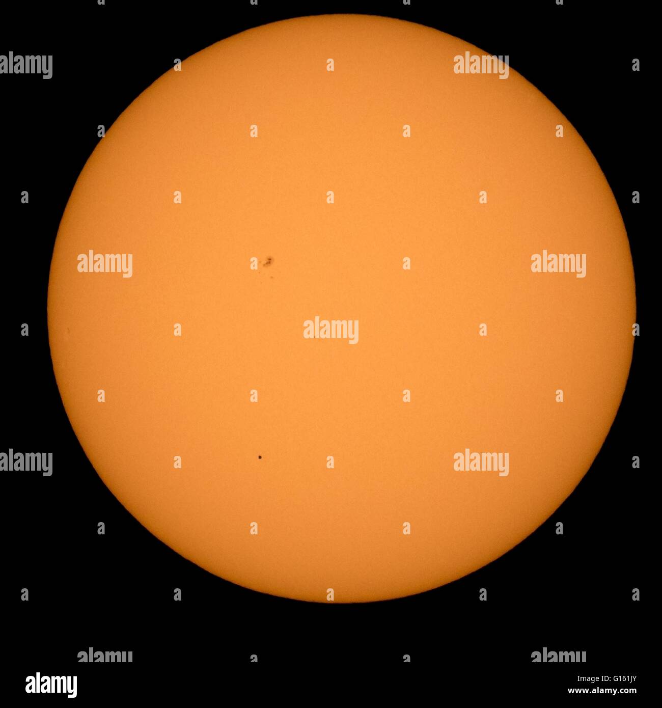 The planet Mercury is seen in silhouette, lower third of image, as it transits across the face of the sun May 9, 2016, as viewed from Boyertown, Pennsylvania. Mercury passes between Earth and the sun only about 13 times a century, with the previous transit taking place in 2006. Stock Photo