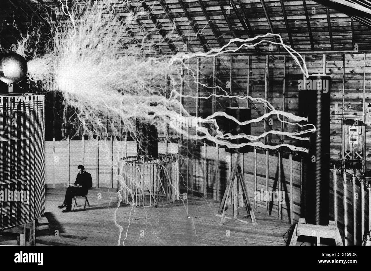 Publicity picture of Tesla sitting in his Colorado Springs laboratory with his 'Magnifying transmitter' generating millions of volts and producing 23 foot long arcs. The image was created using trick photography via a double exposure. The electrical bolts Stock Photo