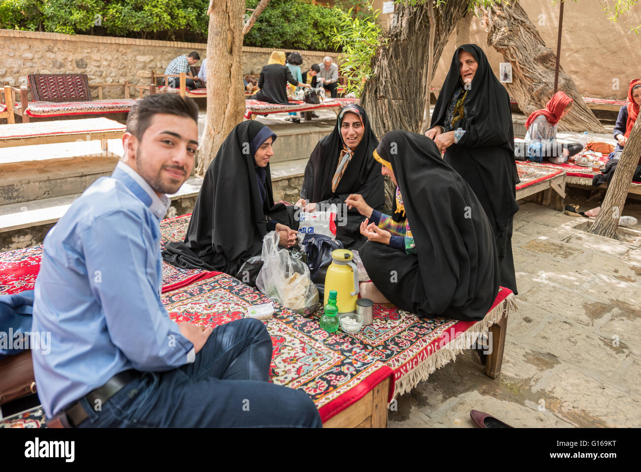 Family picnic in Fin Garden tea house with women wearing chadors. Stock Photo