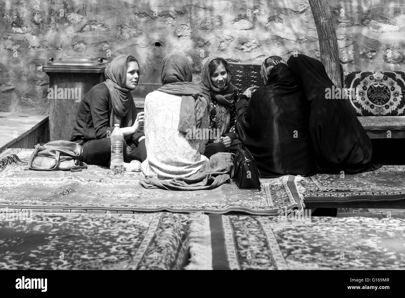 Tourist women in hijabs meet Iranian women in chadors at tea house in Fin Garden, Kashan, Iran. Stock Photo