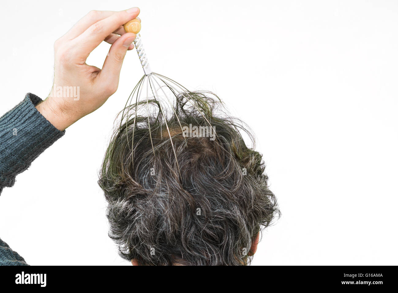 Man relaxes with the Genie head massager. Alternative Therapy. Indian head massage tool, self head massager. Stock Photo