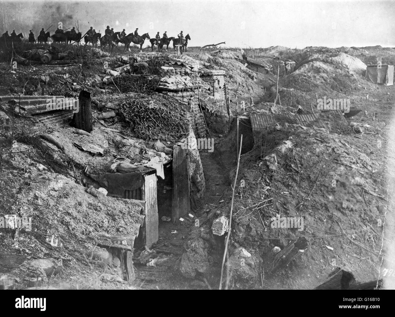 Abandoned British trench which was captured by the Germans; in background, German soldiers on horseback view the scene, circa 1914-18. No location given on caption card. Trench warfare is a form of land warfare using occupied fighting lines consisting lar Stock Photo