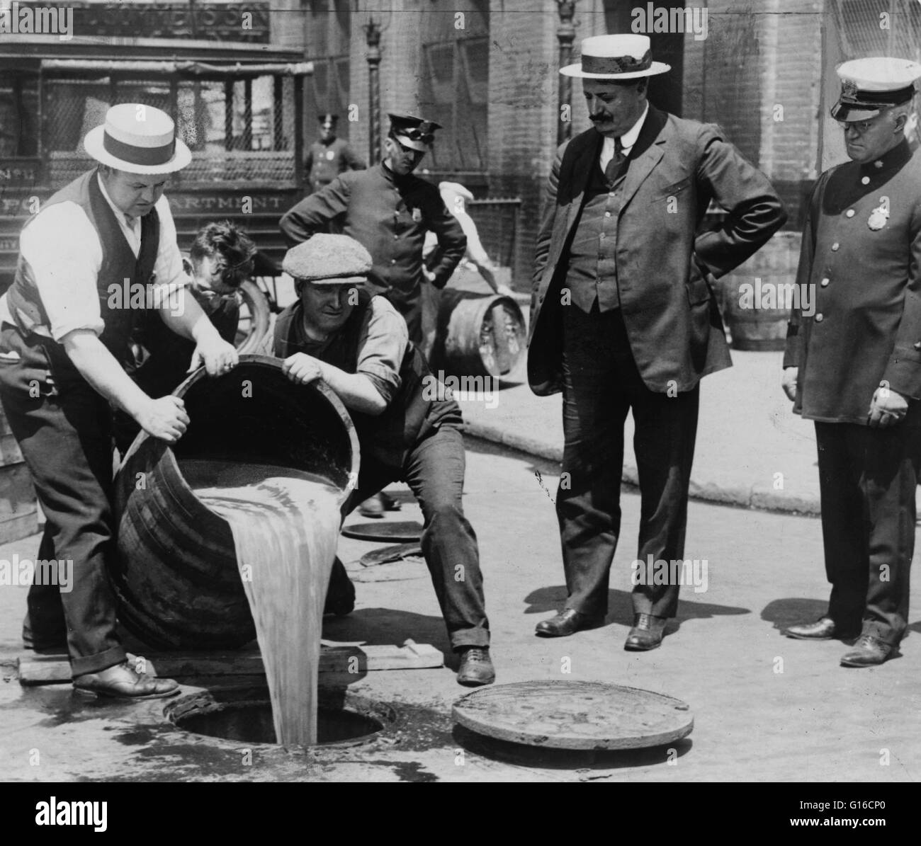 New York City Deputy Police Commissioner John A. Leach, right, watching agents pour liquor into sewer following a raid during the height of prohibition. Prohibition in the United States was a nationwide Constitutional ban on the sale, production, importat Stock Photo