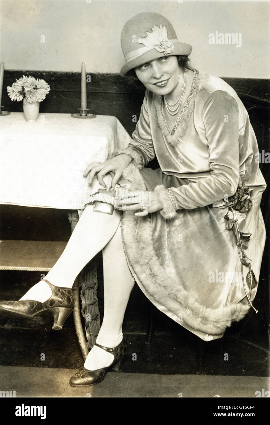 Woman with hidden with flask in garter on leg. Flappers were a 'new breed' of young Western women in the 1920s who wore short skirts, bobbed their hair, listened to jazz, and flaunted their disdain for what was then considered acceptable behavior. Flapper Stock Photo