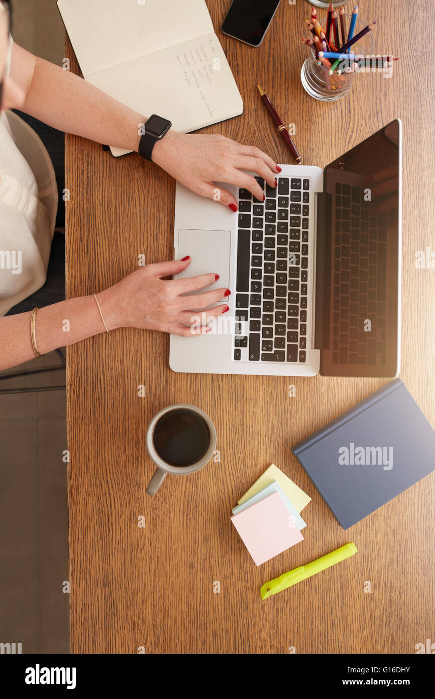 Top view vertical shot of female hands working on a laptop. Woman doing business from home. Stock Photo
