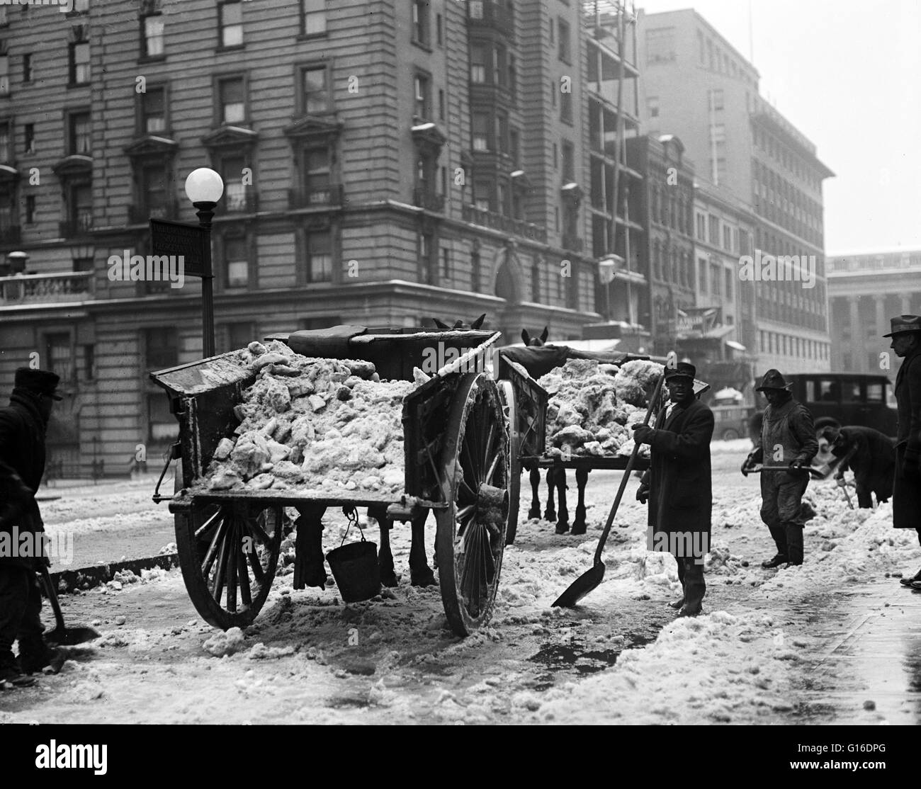 Snow removal; wagons with snow and men with shovels on snow covered street, Washington, D.C. Snow removal at that time consisted of men shoveling the heavy accumulation into wagons which hauled it out of town, where they had to be unloaded by more shoveli Stock Photo