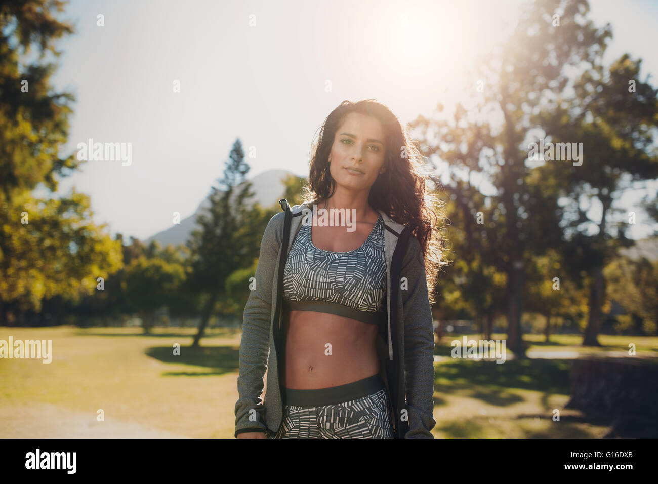 Portrait of confident woman in sportswear at the park. Young middle eastern woman standing outdoors on sunny morning and looking Stock Photo