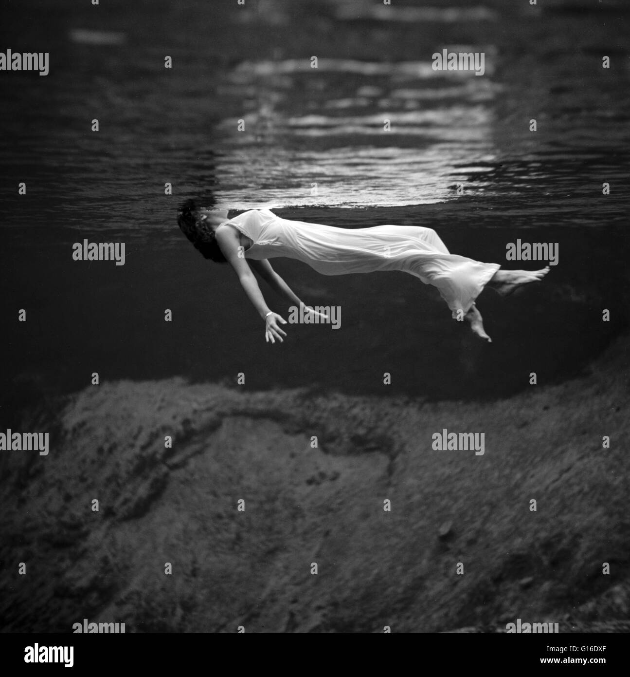 Underwater view of a woman, wearing a long gown, floating in water. Photographed at Weeki Wachee Spring, Florida, 1947. Fashion photography is a genre of photography devoted to displaying clothing and other fashion items. Fashion photography is most often Stock Photo
