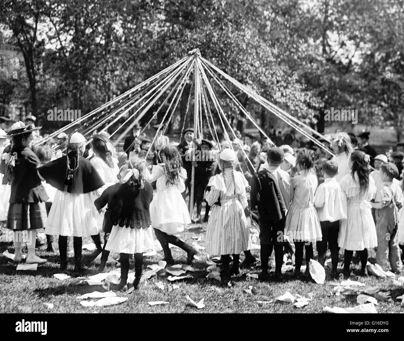 Entitled: 'May pole dance, Central Park, New York.' Maypole dancing is a form of folk dance from Germany, England, and Sweden. There are two forms. The first and most popular consists of dancers that perform circle dances around a tall, garland-festooned Stock Photo