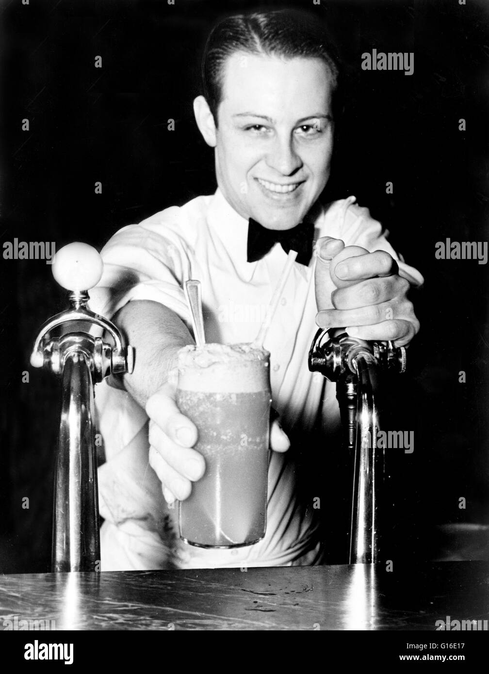 Entitled "Soda jerk passing ice cream soda between two soda fountains