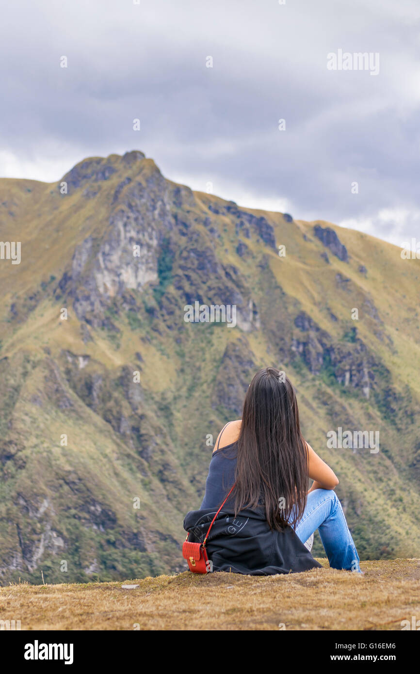 Back view of adult young woman with black straight hair contemplating the landscape of andes range in Quito, Ecuador Stock Photo