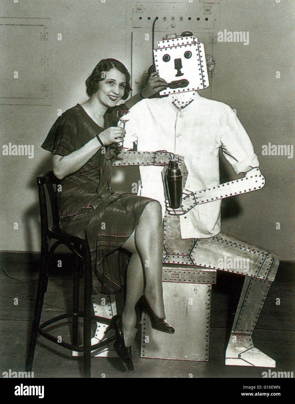 A young bar maid met the future. A cocktail robot at a bartender's school in New York, 1933. The term 'robot' was first used to denote fictional automata in a 1921 play R.U.R. by the Czech writer, Karel Capek.  In 1928, one of the first humanoid robots wa Stock Photo