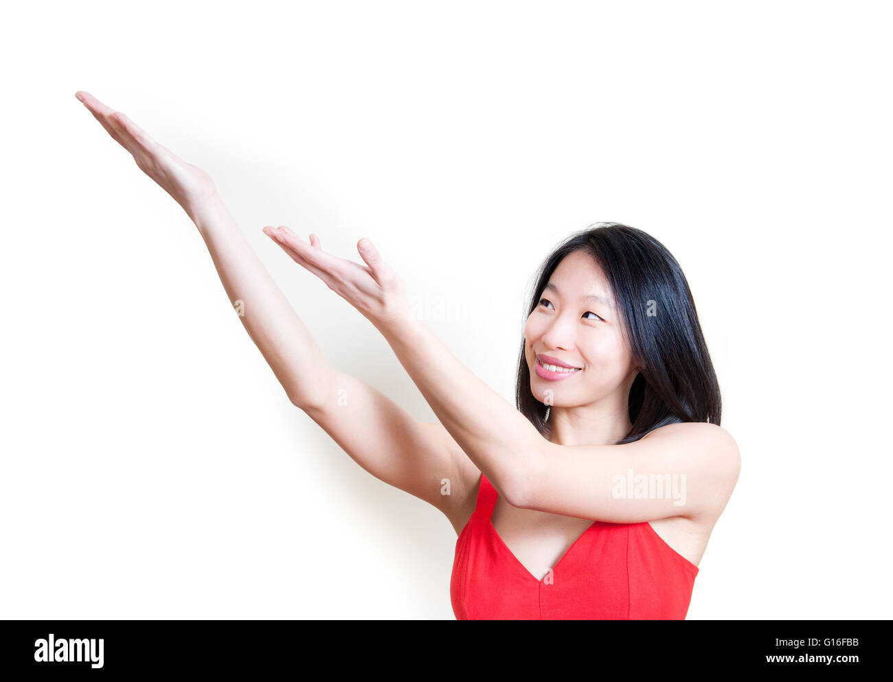 Young beautiful asian woman in red dress smiling and pointing out isolated on white background portrait Stock Photo