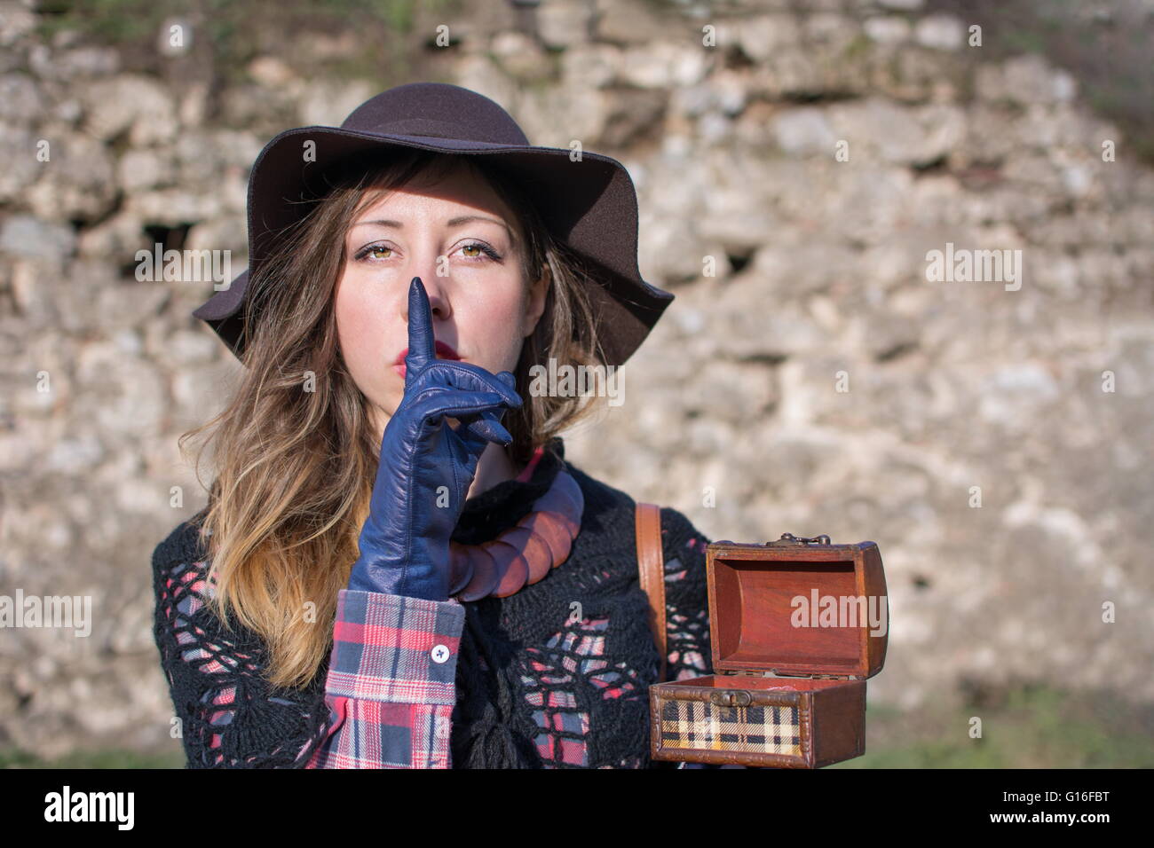 Mysterious young woman holding an old wooden box outdoors and demanding silence. Shhh! Stock Photo