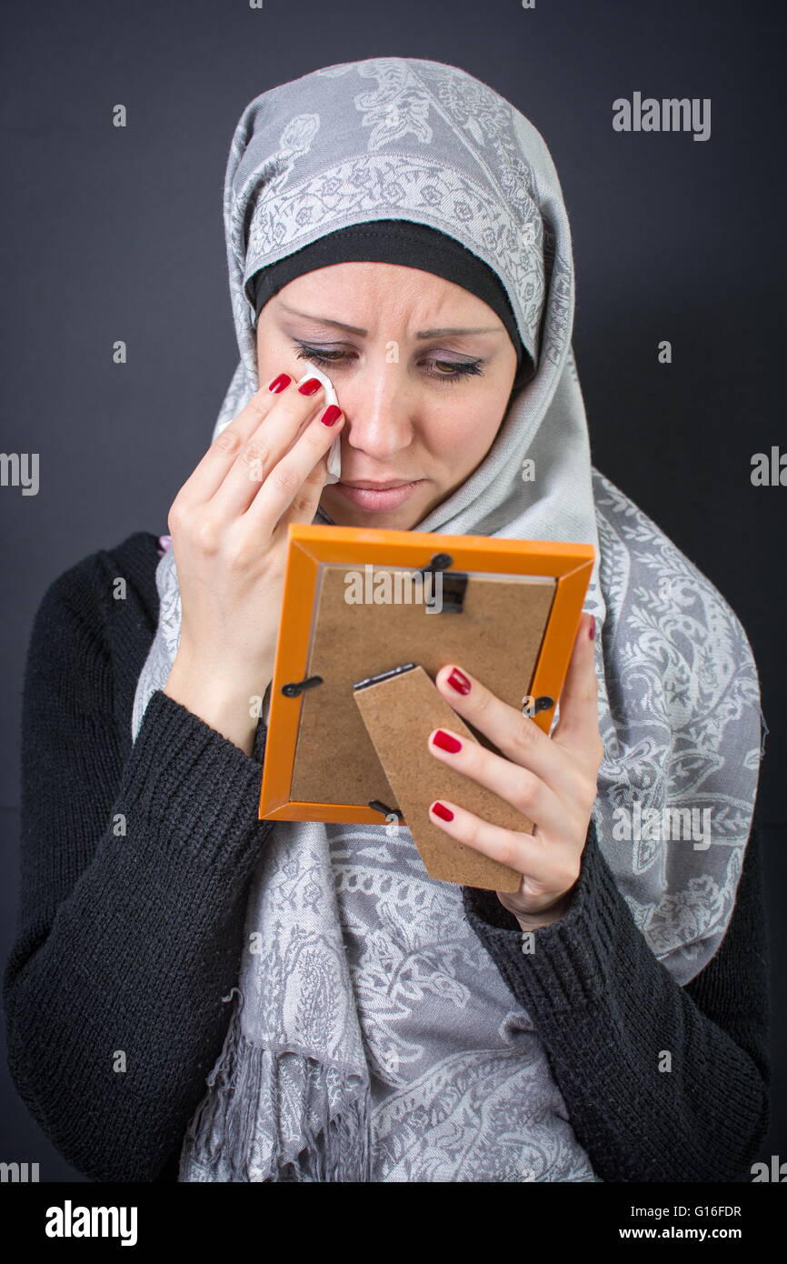 Muslim woman moaning over an old photograph in a frame Stock Photo