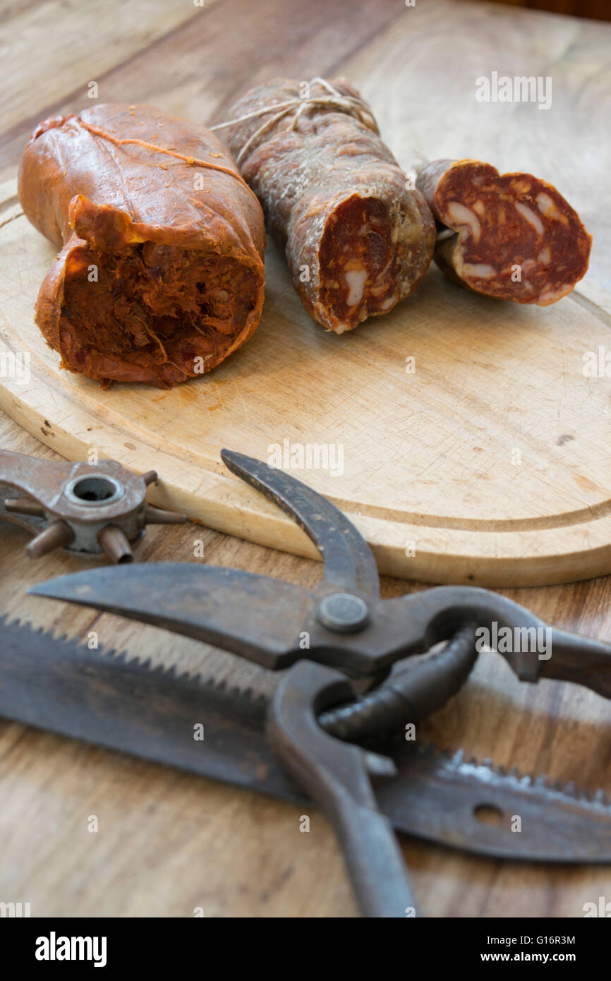nduja and calabrese soppressata near old utensils of work Stock Photo