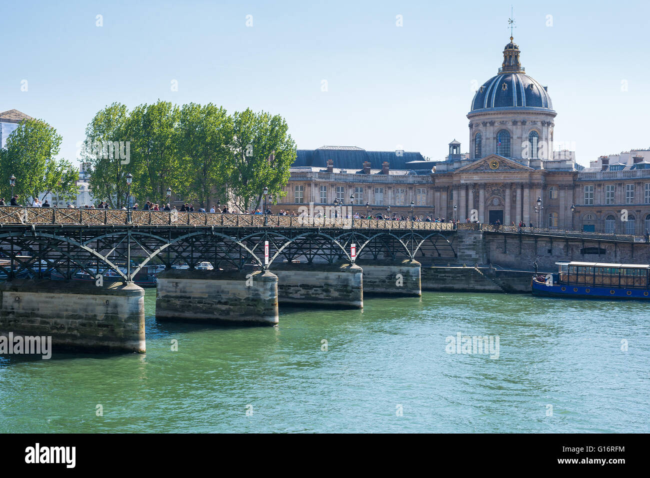 Pedestrians on the Pont des Arts, Paris, it's railings covered in padlocks. Institute de France in the background. Stock Photo