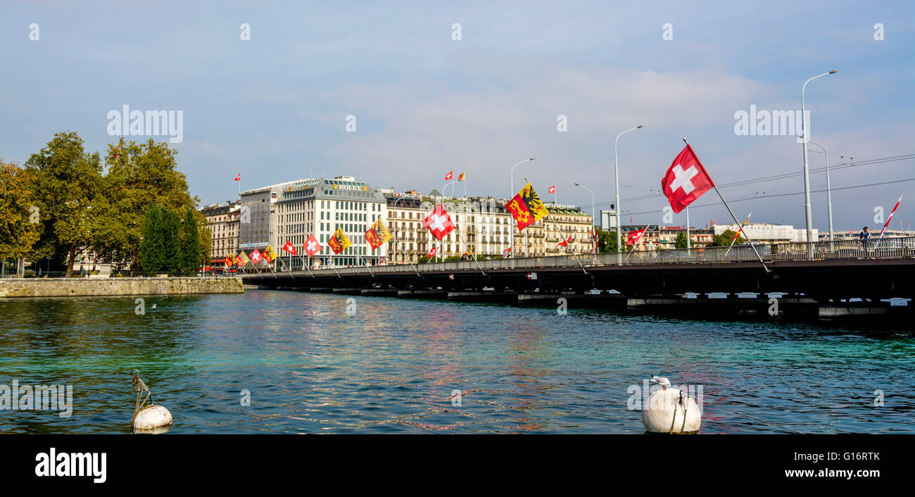 Pont Mont-Blanc in Geneva showcases Swiss flags and stunning views of the Rhone River on a clear day, Switzerland Stock Photo