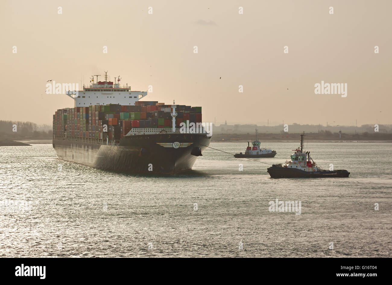 Tug boats assisting container ship by leaving Dunkirk Harbour Stock Photo